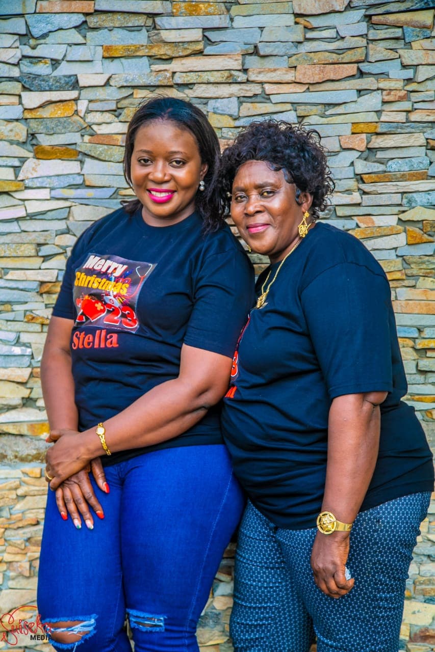 Two members of the CEYOFE team standing together in front of a stone wall, smiling to camera