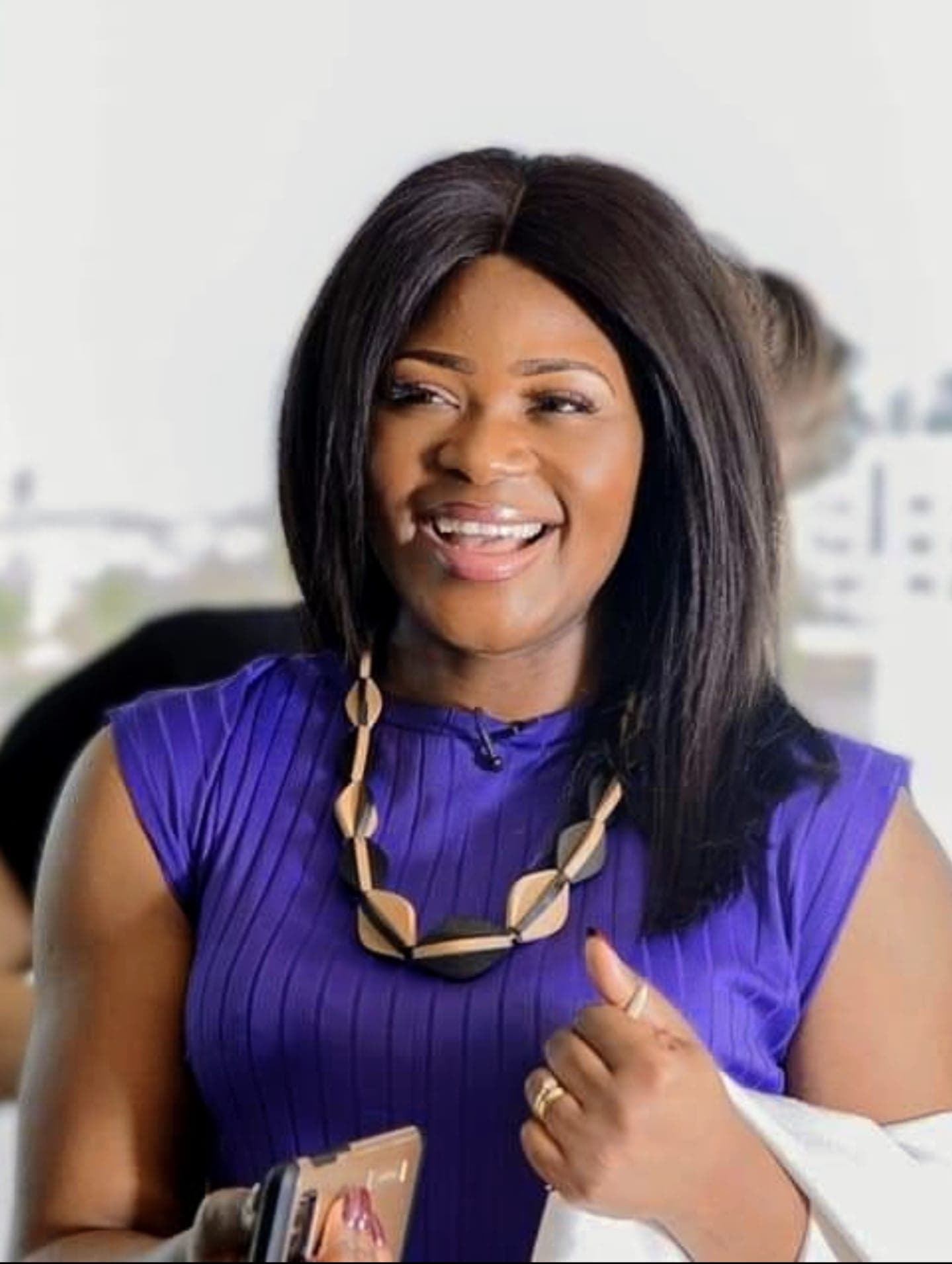 Portrait of TMTF founder Dorothy Akoh-Arrey, smiling to camera in a purple top, giving a thumbs up